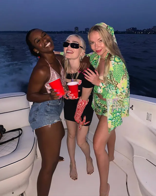 Meg Donnelly posing barefoot with friends on a boat.