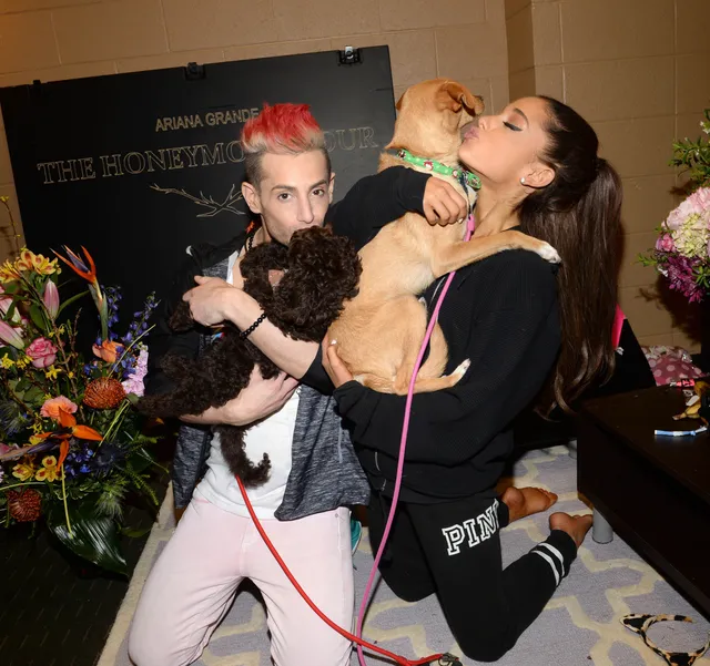 Ariana Grande kneeling beside guests backstage.