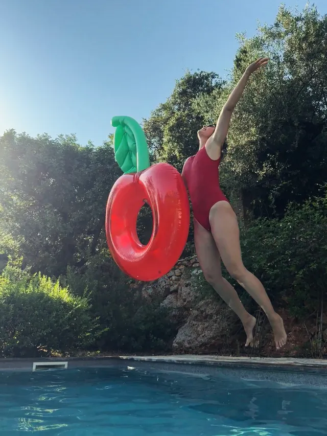 Maria Sharapova jumping barefoot towards a swimming pool while holding an inflatable ring.