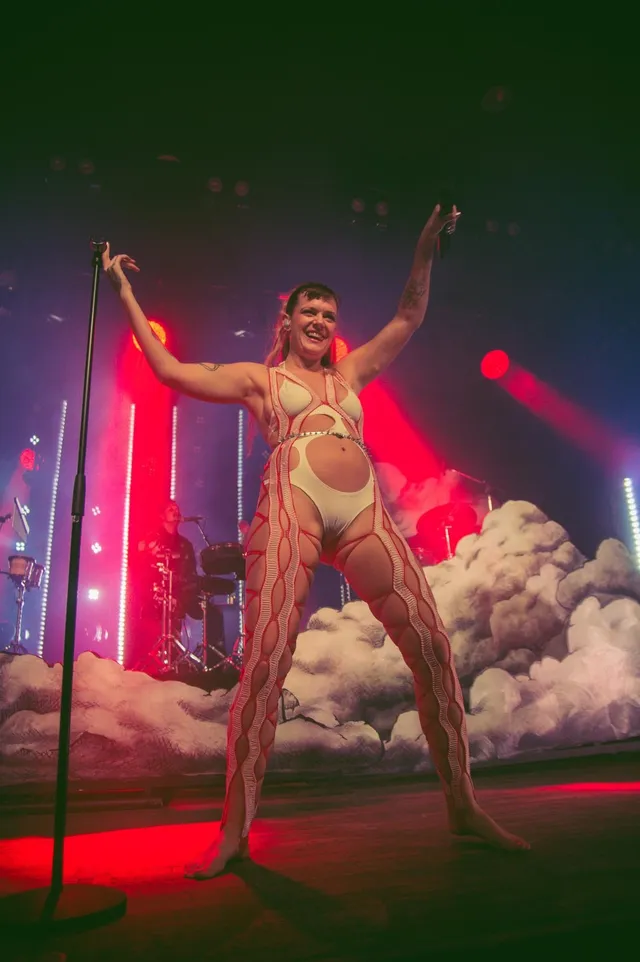 Tove Lo singing barefoot on stage in a patterned outfit.