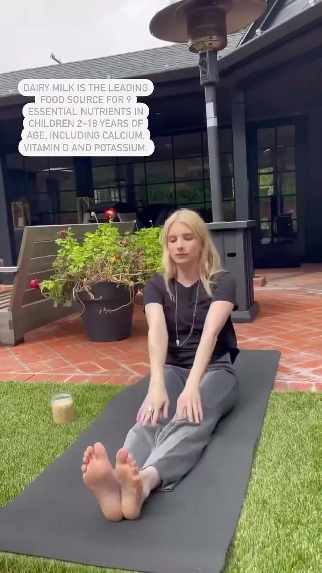 Emma Roberts stretching barefoot on an outdoor exercise mat.