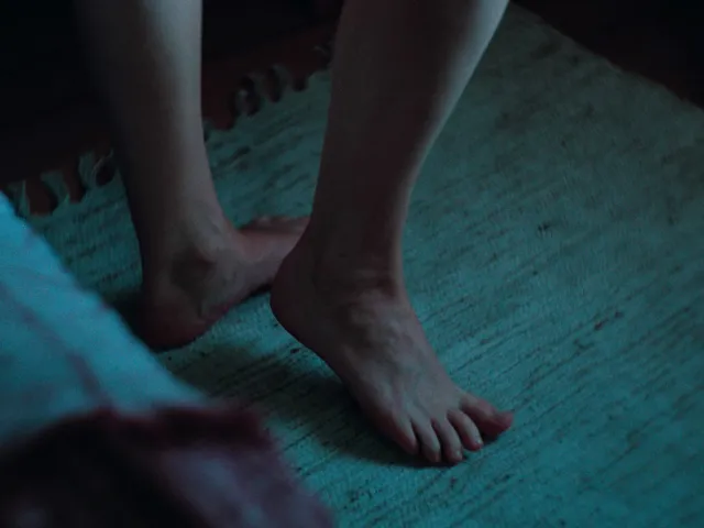 Jennifer Lawrence standing barefoot on a rug in a screen scene.