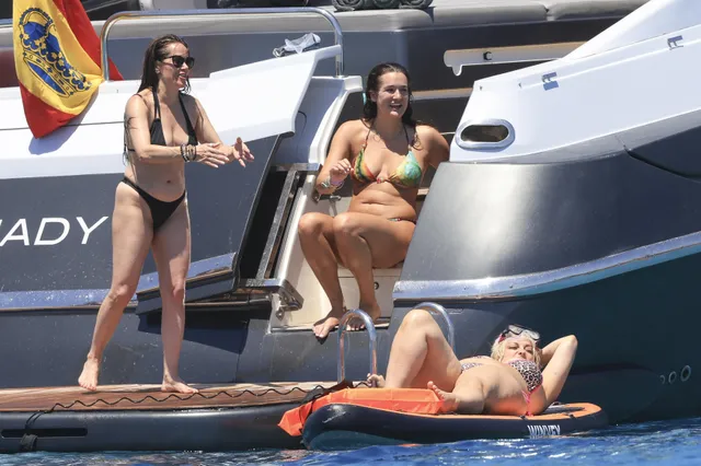 Bebe Rexha lying barefoot on a paddleboard beside other adults.