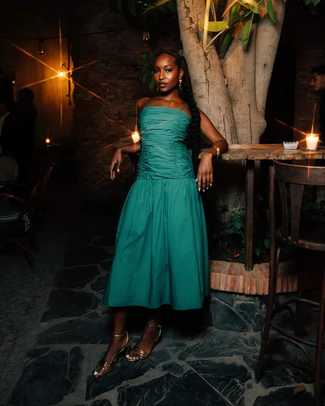 Carlacia Grant posing outdoors in a green dress and heels.