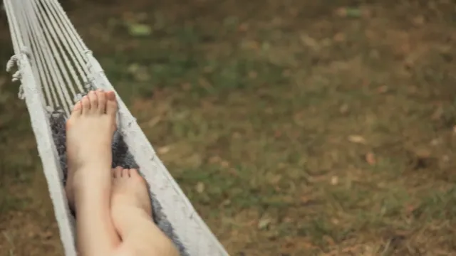 Natalie Dormer resting on a hammock outdoors.