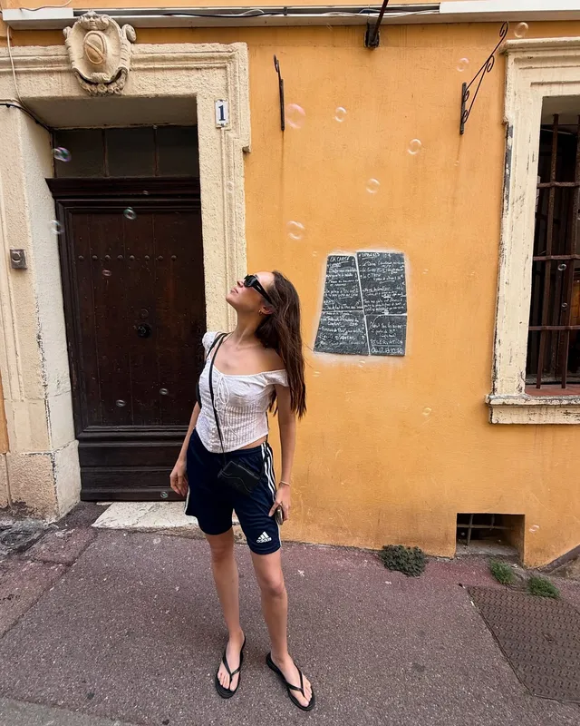 Alycia Debnam-Carey standing outside a building in shorts and flip-flops.