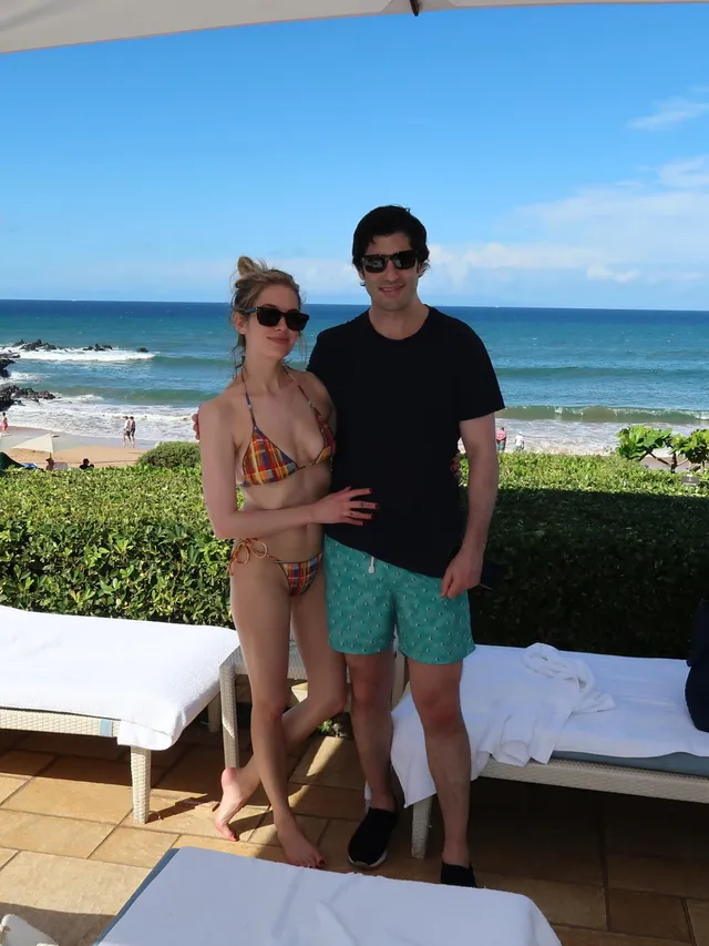 Ashley Benson standing beside a companion on a seaside terrace.