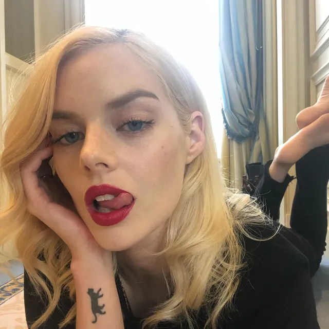 Samara Weaving taking a selfie with a bare foot raised behind her.