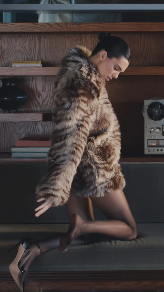 Kendall Jenner kneeling in metallic heels and a fur coat.