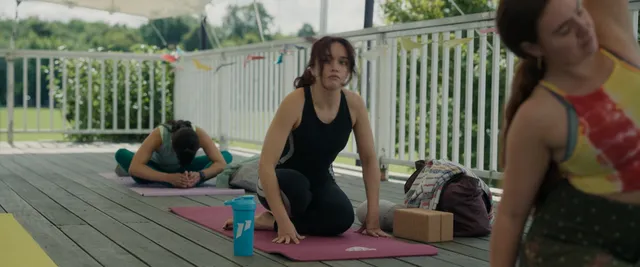 Olivia Cooke kneeling on an outdoor yoga mat.