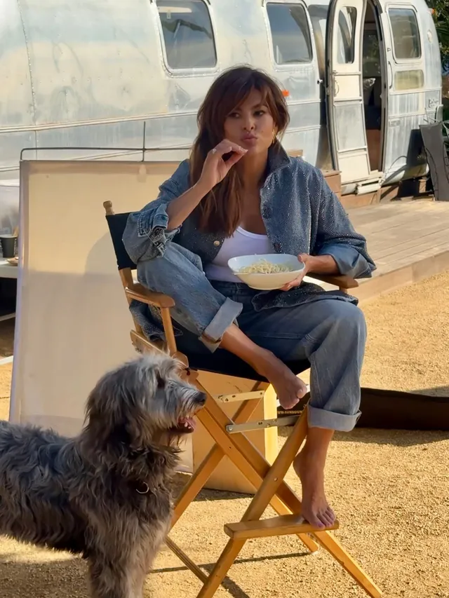 Eva Mendes sitting in a folding chair beside a dog.