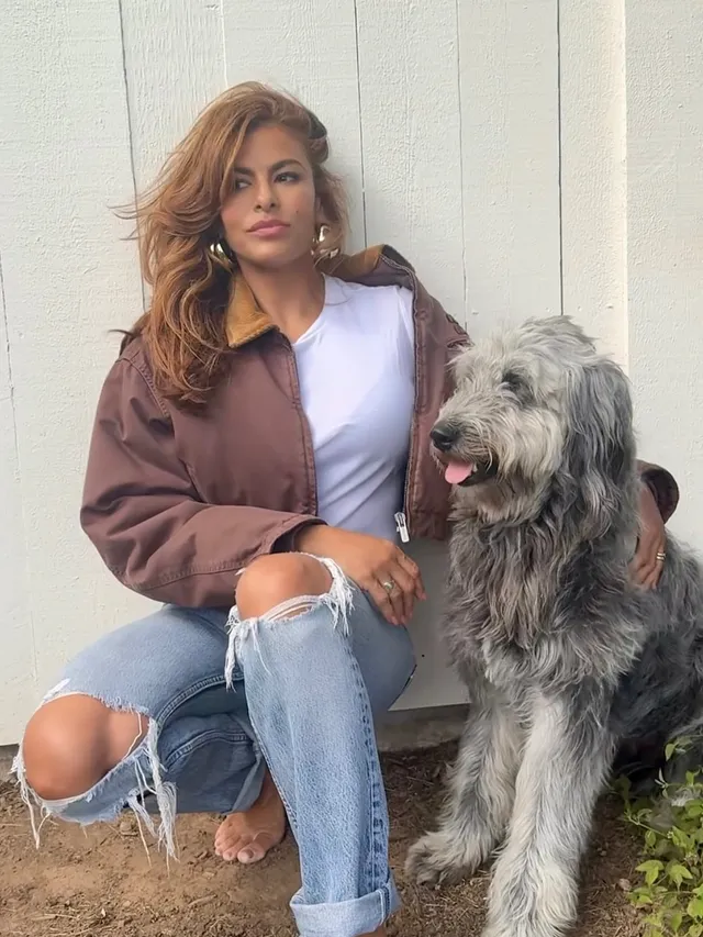Eva Mendes sitting beside a dog in ripped jeans.