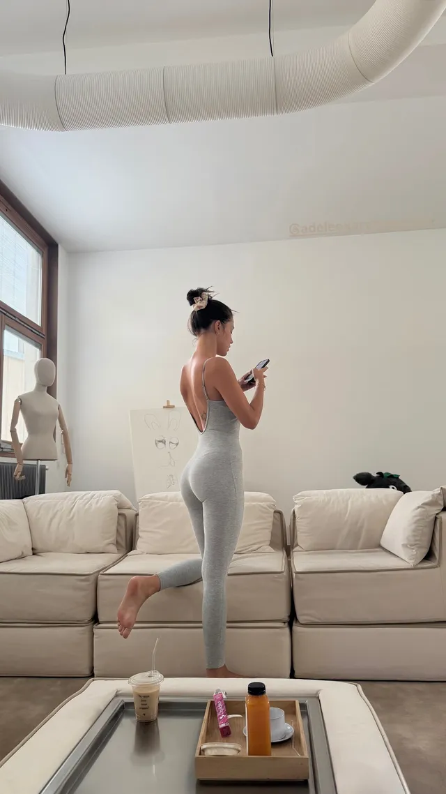 Adèle Exarchopoulos standing beside a sofa in pale leggings.