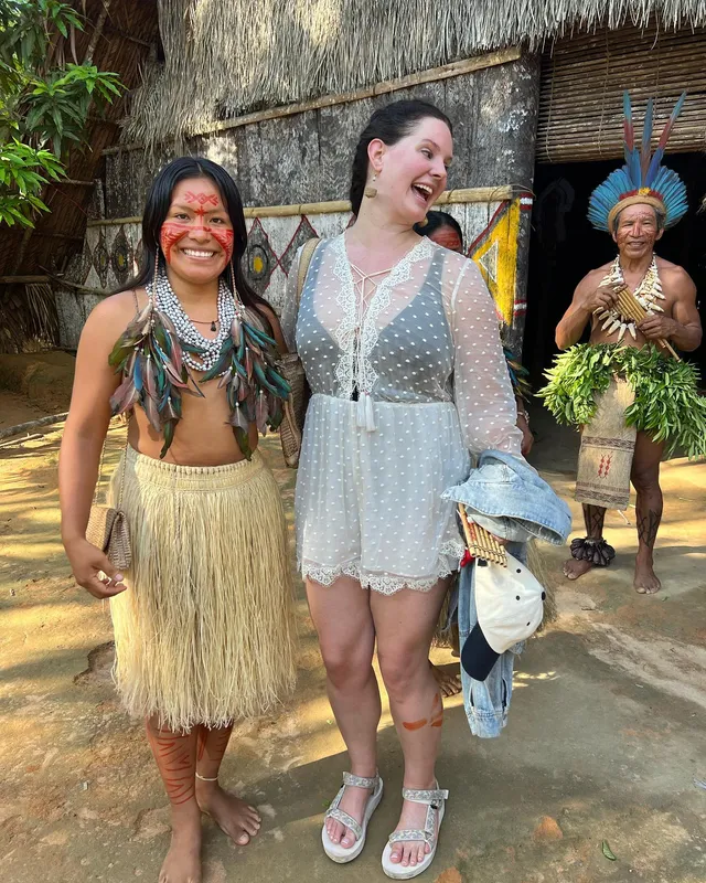 Lana Del Rey standing with other people in pale flat sandals.