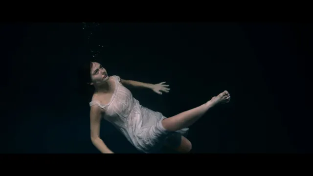 Emily Alyn Lind shown floating underwater in a pale dress.