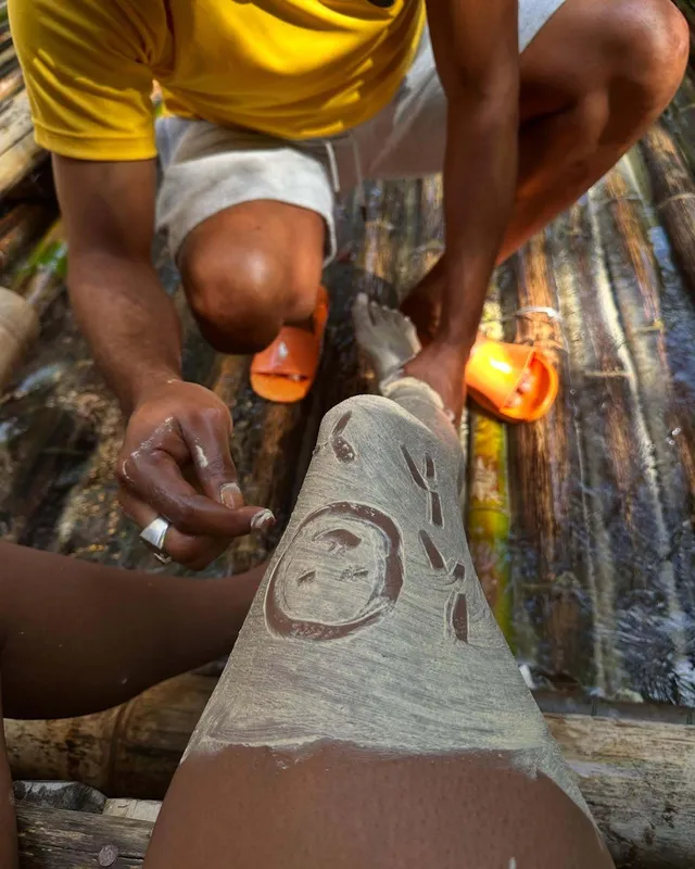 Carlacia Grant shown receiving clay on a bare lower leg outdoors.