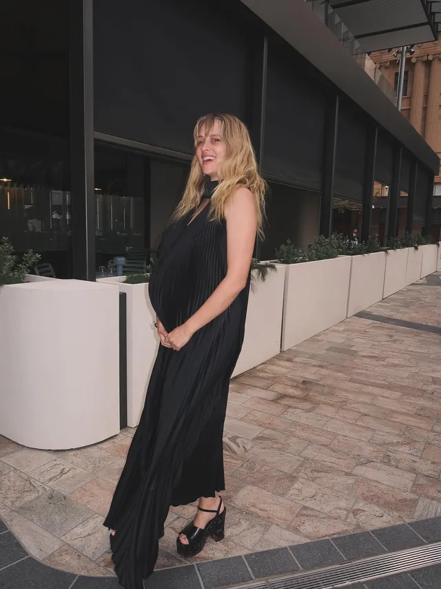 Teresa Palmer posing outdoors in a long black dress.