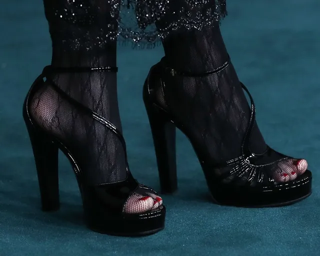 Billie Eilish a close-up of black platform heels over sheer tights.