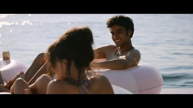 Emily Alyn Lind reclining barefoot on a pool float in a scene.