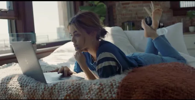 Lucy Hale using a laptop while lying on a bed during a screen scene.