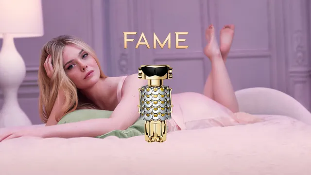Elle Fanning lying on a bed in an advertisement for a fragrance.