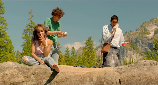 Zoë Kravitz posing beside other performers on a rock.