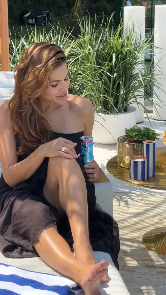 Eva Mendes sitting outdoors holding a drink.