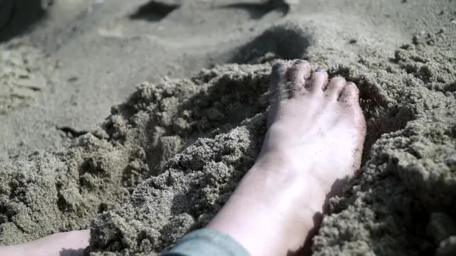 Elisha Cuthbert resting a bare foot in sand.