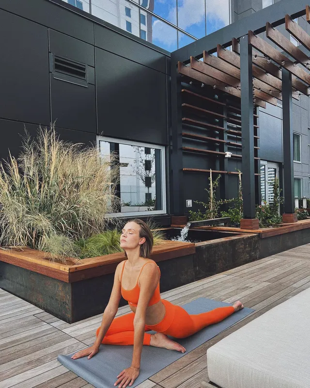 Josephine Skriver stretching barefoot on a mat in an orange exercise outfit.