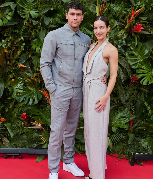 María Gabriela de Faría posing in a pale trouser suit and heels with a guest.