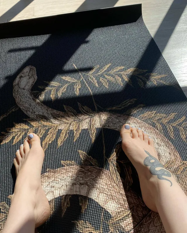 Dove Cameron showing bare feet beside a patterned rug.