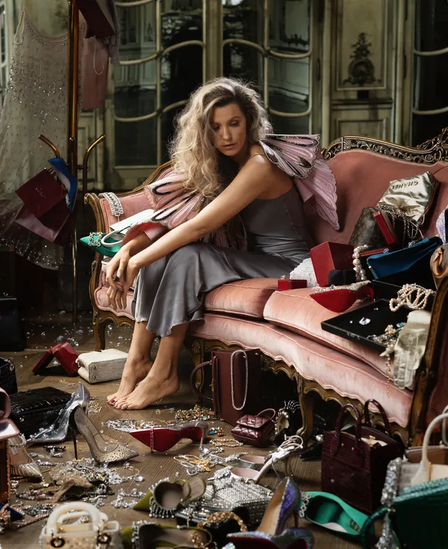 Blake Lively sitting barefoot on a sofa surrounded by shoes.