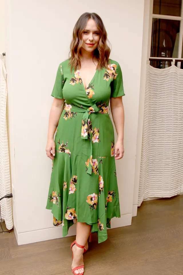 Jennifer Love Hewitt posing in a green floral dress and red heels.