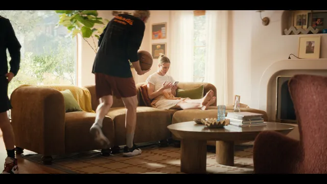 Kristen Bell sitting in a living room with other people in a television scene.
