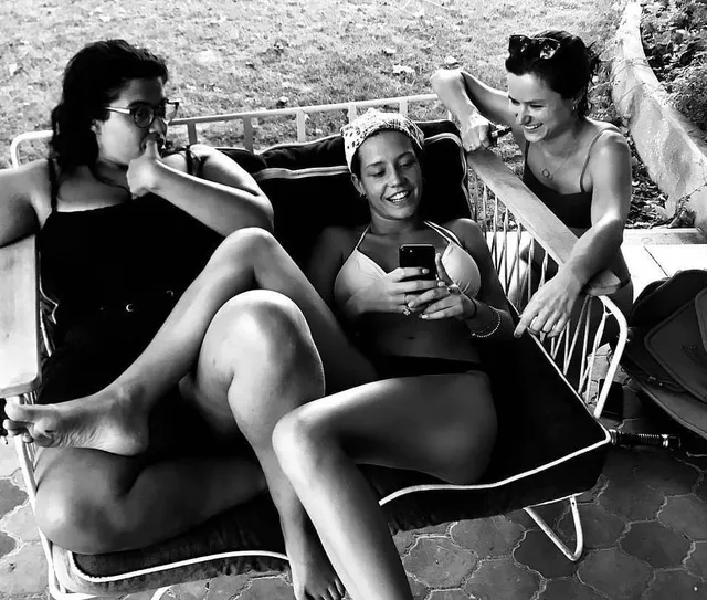 Adèle Exarchopoulos relaxing on loungers with friends in a monochrome photo.