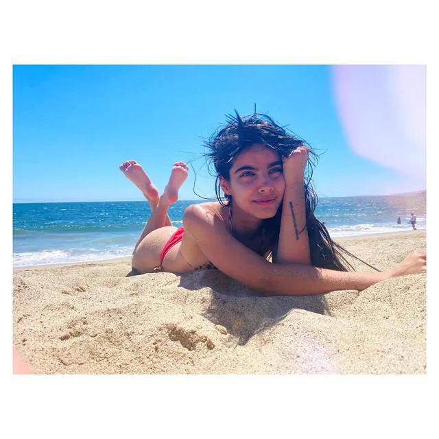 María Gabriela de Faría lying barefoot on a beach.