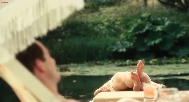 Keira Knightley a reclining outdoor screen scene with bare feet raised.