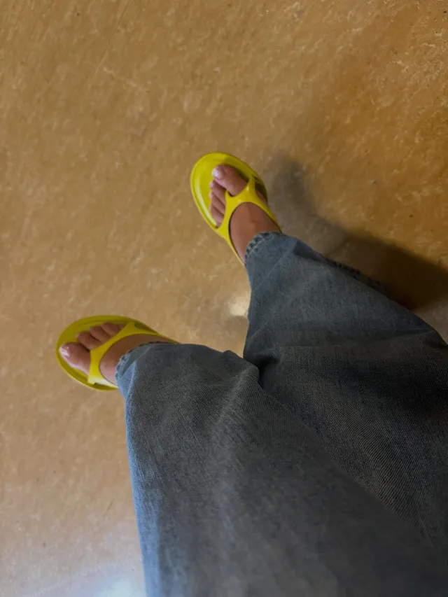 Madison Bailey shown from above wearing jeans and yellow sandals.