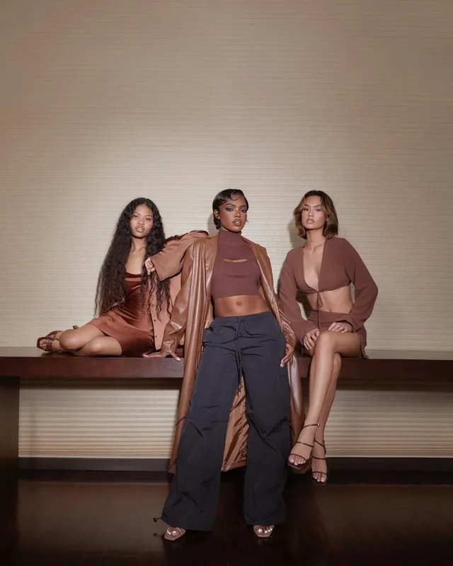 Ryan Destiny posing with guests in a brown outfit and open-toe heels.