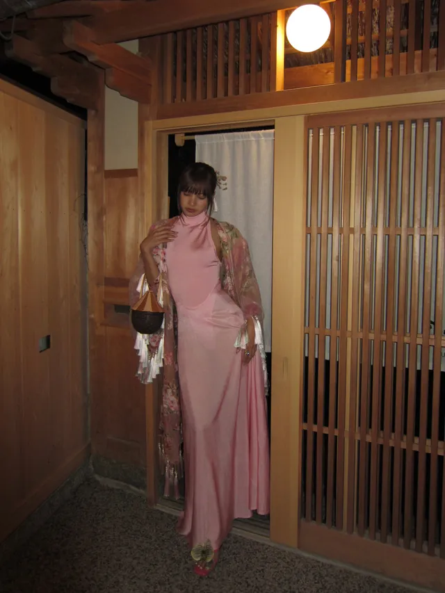 Lisa (Lalisa Manobal) standing in metallic heels and a long pink dress in an indoor hallway.