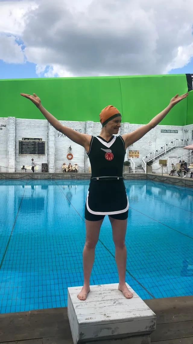 Daisy Ridley standing on a diving board beside a pool.