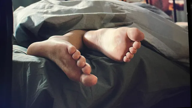 Nicole Wallace shown in a close-up of bare feet extending from bed covers.