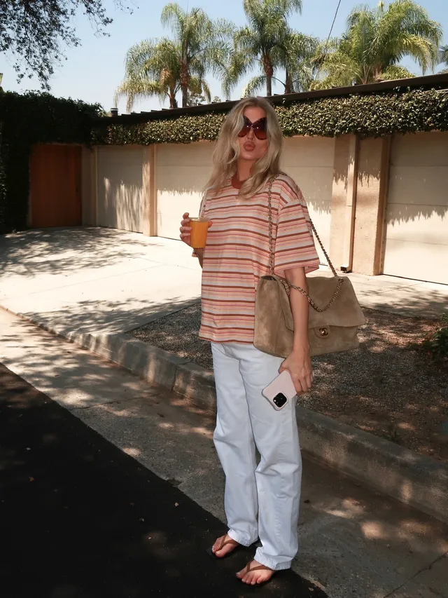 Elsa Hosk wearing flat sandals beneath white trousers with a striped shirt.