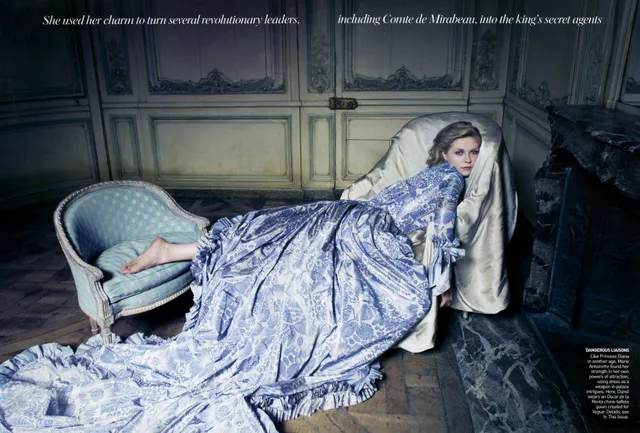 Kirsten Dunst reclining on a bed in a patterned blue dress.