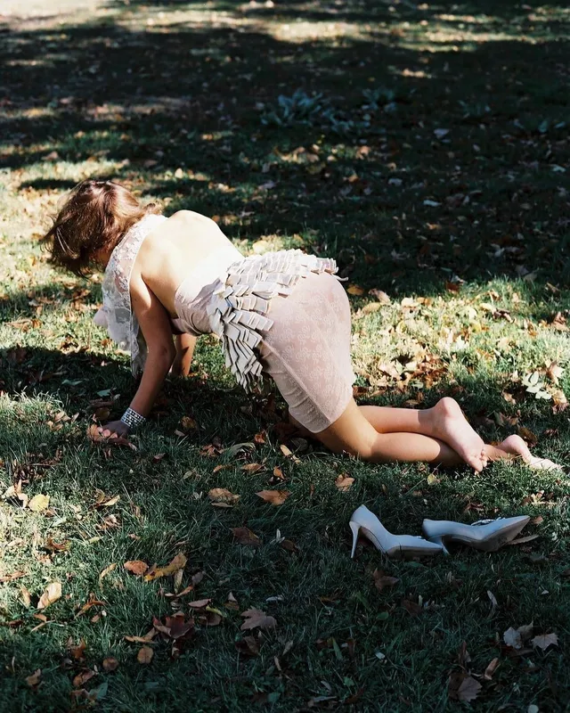 Adèle Exarchopoulos kneeling on grass in a pale skirt.