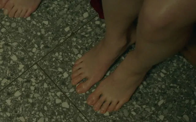 Jisoo standing barefoot on a patterned stone floor.