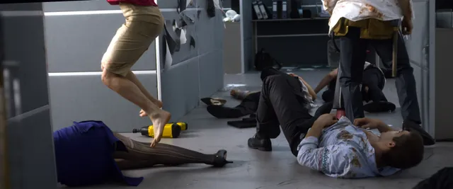 Samara Weaving walking barefoot past people on a floor in a film scene.