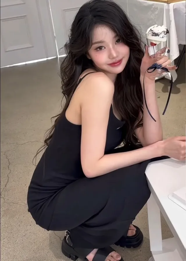 Jang Wonyoung crouching beside a counter in a black outfit and heels.