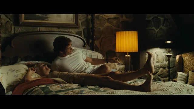 Kate Bosworth resting her legs on a bed in a screen scene.