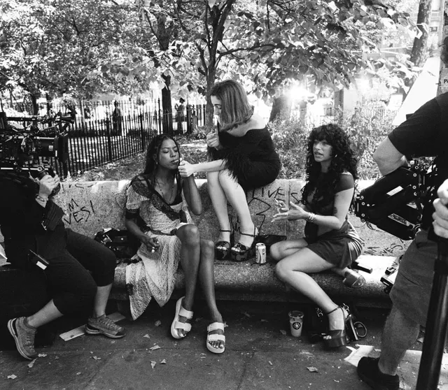 Odessa A'zion sitting outdoors with cast members in flat sandals.